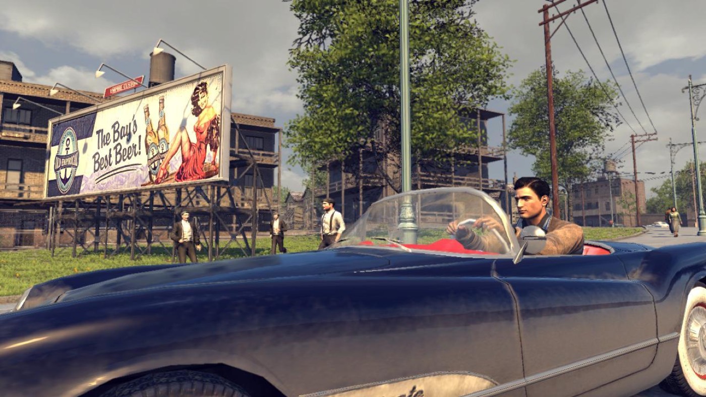 A period convertible cruising past vintage billboards in daylight